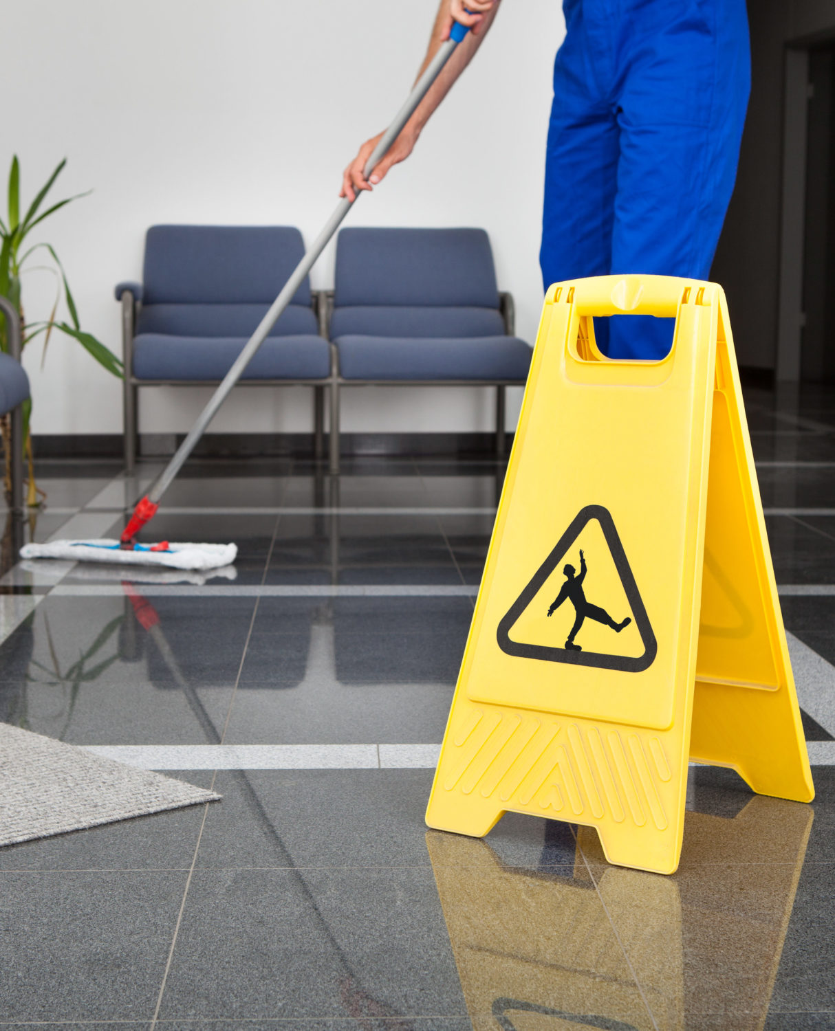 Janitor cleaning with a wet floor sign on the ground